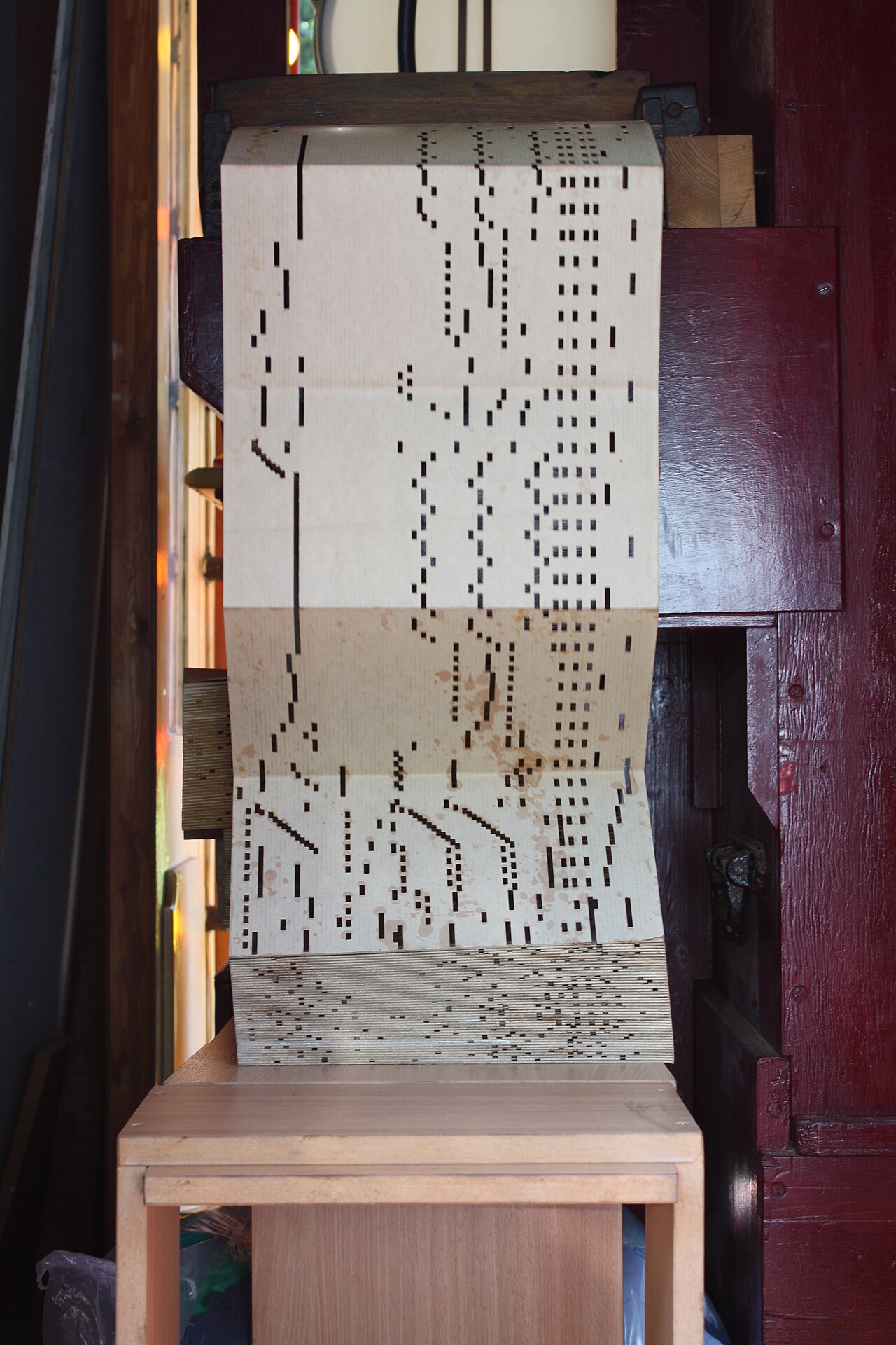Figure 2 — Fan-folded cardboard book music feeding a fairground-organ keyframe; the punched slots are the program