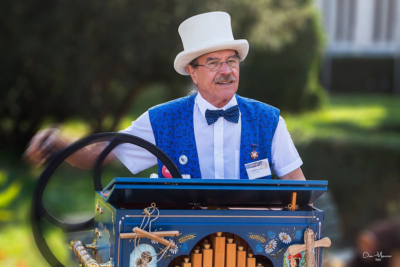 Figure 3 — A portable street ("monkey") barrel organ: the crank both turns the pinned barrel and raises the wind, and the notched head disc selects one of the barrel's tunes.