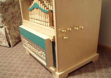 Figure 3 — A John Smith organ's optional glockenspiel: tuned bars struck by stainless-rod beaters with MIG-wire return springs, mounted in the base of the case.