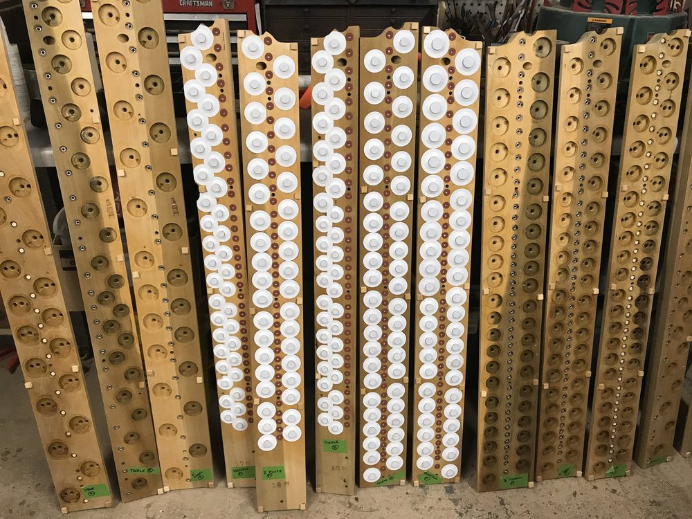 Figure 3 — A valved John Smith organ's pillow-pouch board and valve box: dowel-and-leather valves on brass stems seated above the pouches, the pneumatic amplifier that lets one small roll drive four ranks.